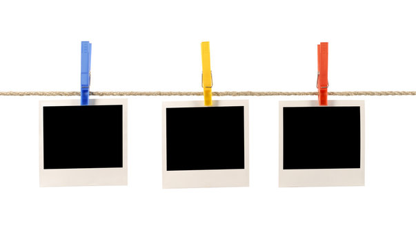 Three blank polaroid style instant photo frame prints on a rope string or washing line with clothespegs or clothes pegs