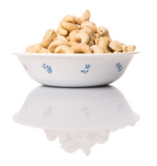 Raw cashew nuts in a white bowl over white background