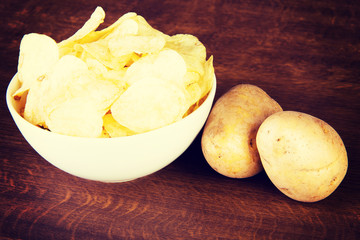 Potatoe chips in a bowl and potatoes.