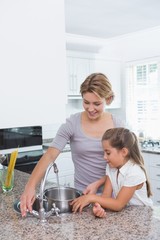 Mother and daughter filling pot with water