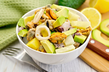 Salad seafood and avocado in bowl on board