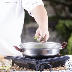 Chef putting vegetable in pot before cooking noodle
