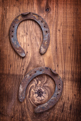two old rusted horsehoes on vintage wooden board happy concept