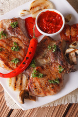 pork steak with grilled vegetables on plate, vertical top view