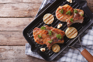 Pork steak with onion in a pan grill, top view horizontal