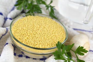 Fototapeta na wymiar Raw couscous in glass bowl with garlic and parsley