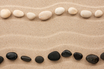 Fototapeta na wymiar Two rows of white and black stones on the sand