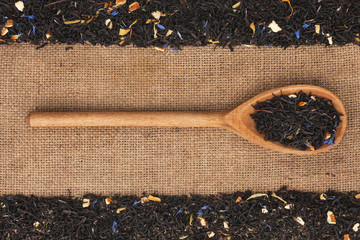 Wooden spoon with  black  tea  lies on  sackcloth