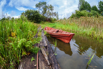 Fishing wooden boat at the lake in summer day