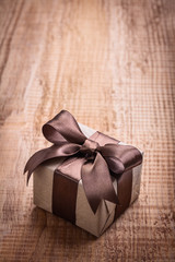 small square vintage gift box with brown bow on old wooden board