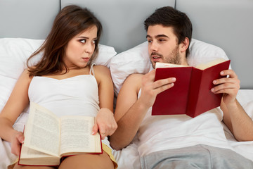 Happy Couple Sitting in Bed Reading Books at Home in Bedroom