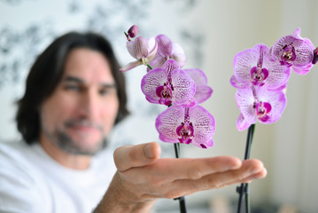 man with a pink orchid in the room