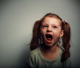Shouting angry kid girl with open mouth and negative look