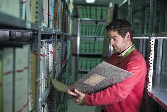 Encargado realista de archivo mira anotaciones en libro