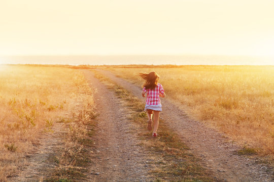Little girl running in backlit meadow