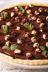 tart with chocolate and hazelnuts on a table closeup. Vertical