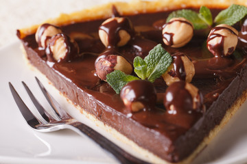 piece of chocolate tart with hazelnuts on a plate macro.