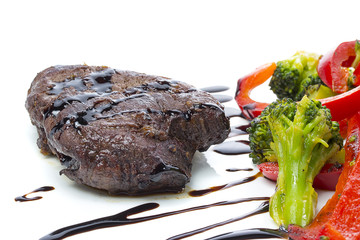 A beef stake with steamed green arranged on a white plate