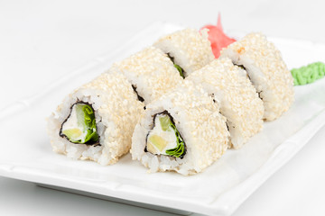 Three-cornered sushi roll with fish, cucumber and green salad.