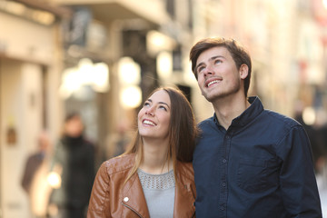 Couple looking above in the street of a city