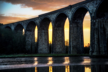 Viaduct silhouette with sunrise and clouds behind