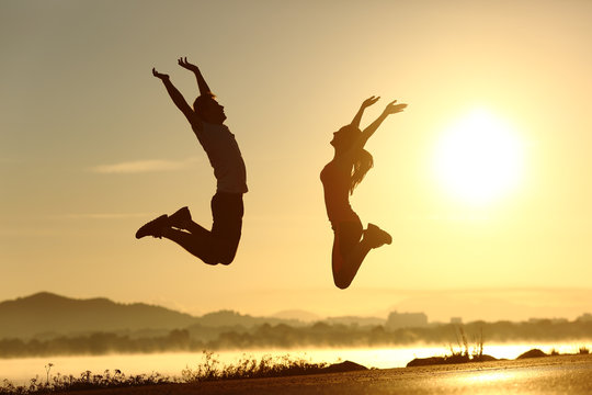 Fitness couple jumping happy at sunset