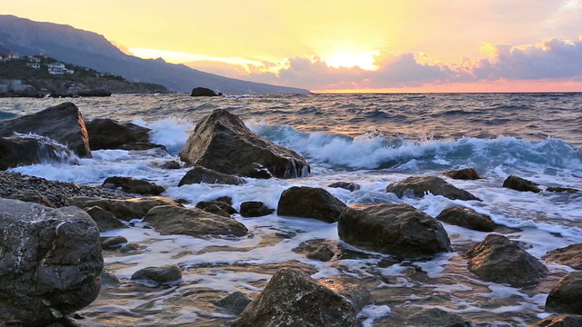 Big waves break about stones at sunrise