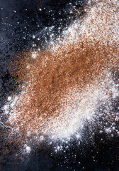 Dusted wheat flour and cocoa powder on dark background