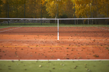 Fototapeta premium Empty tennis court covered with leaves