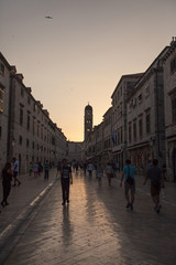 Fototapeta na wymiar DUBROVNIK, CROATIA - MAY 26, 2014: Tourists walking on Stradun at sunset. Stradun is 300 meters long main pedestrian street in Dubrovnik.