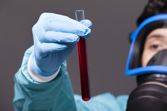 Scientist holding a sample of blood on grey background