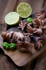 Rustic wooden cutting board with baby octopuses, studio shot