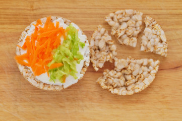 Fototapeta na wymiar Rice cakes with white low fat cheese spread, carrot and cucumber
