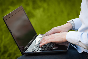 Businessman pressing modern laptop computer on colorful backgrou