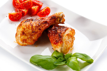 Grilled chicken legs and vegetables on white background