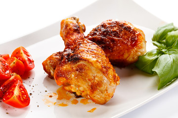 Grilled chicken legs and vegetables on white background