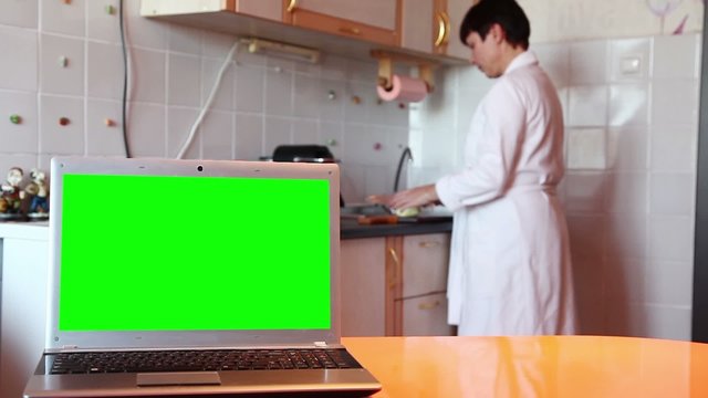 Laptop.  Green screen. Woman prepares dinner.