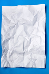 Wrinkled white piece of paper over a blue background.