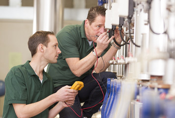 Two male technician repairing agriculture machinery..