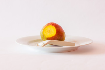 Mango mit Sparschäler auf Teller, angeschnitten