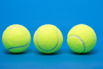 Three isolated tennis balls over a blue background.