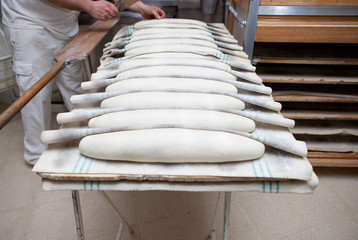 Fototapeta na wymiar Baker putting dough into the oven
