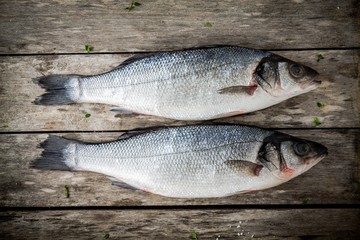 two raw seabass on a rustic wooden table