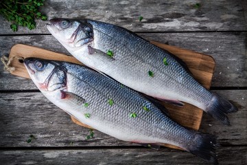 two raw fresh sea bass on a cutting board with thyme