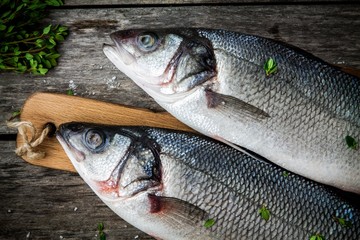 two raw fresh sea bass closeup on a rustic wooden table