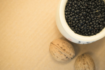 black lentils  in a porcelain cup and walnuts