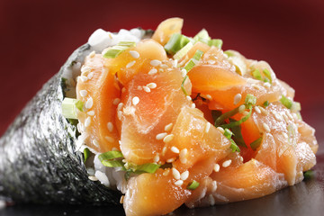 A close up of salmon temaki against a red background
