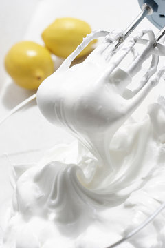 A close up of a kitchen whisk whipping cream to make a meringue