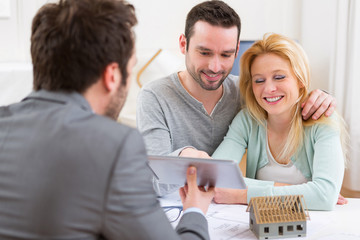 Fototapeta premium Real estate agent present project on tablet to a young couple