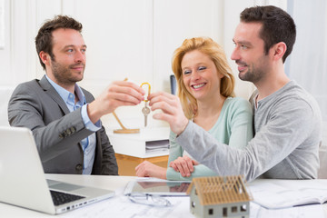 Real estate agent delivers keys of new house to young couple